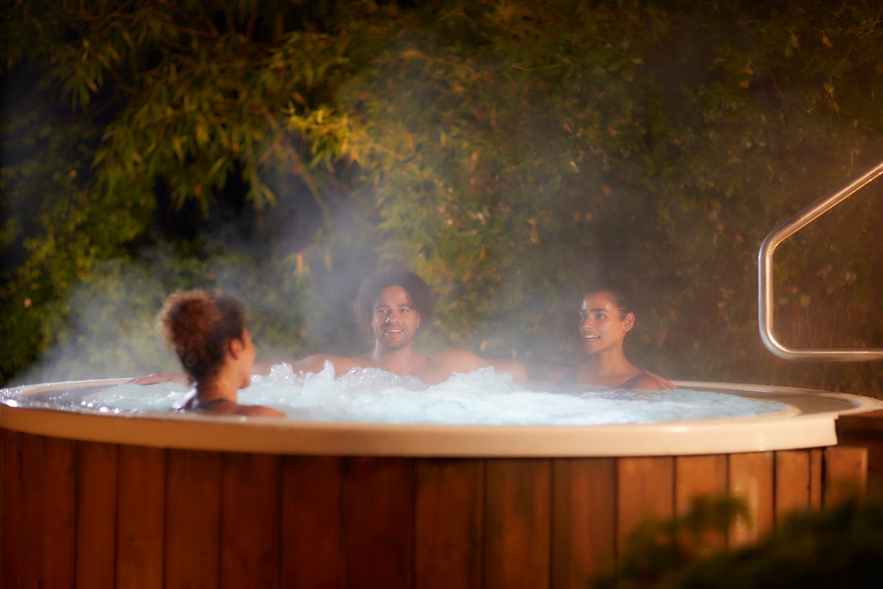 Men and women soaking in a bubbling outdoor hot tub.